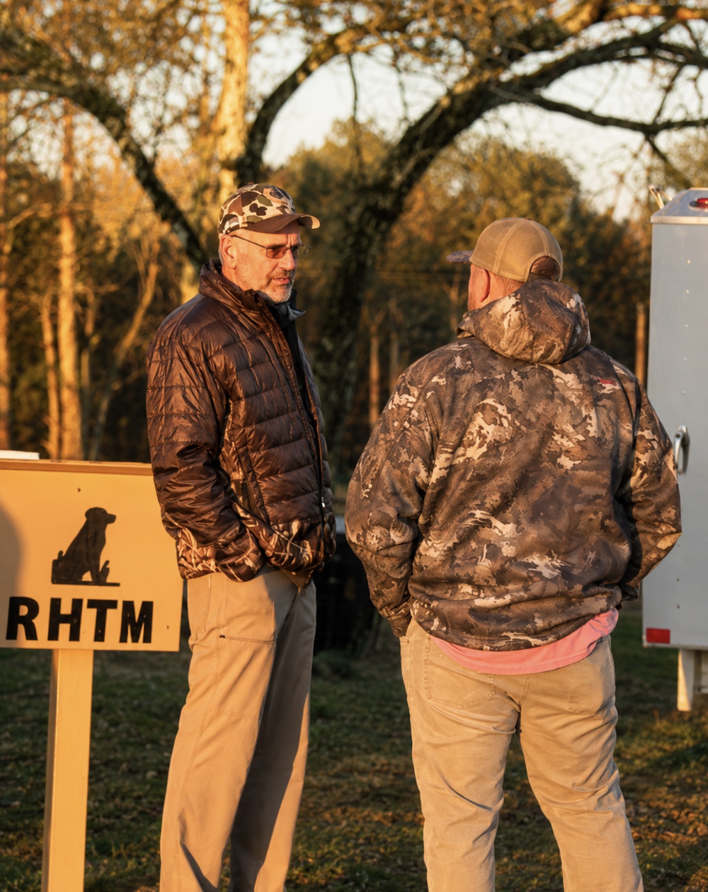 Two men talking by the RHTM sign at golden hour